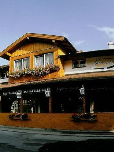 A charming, traditional restaurant with a wooden facade and floral decorations. The terrace is inviting and ideal for guests. | © Restaurant Schattleitner