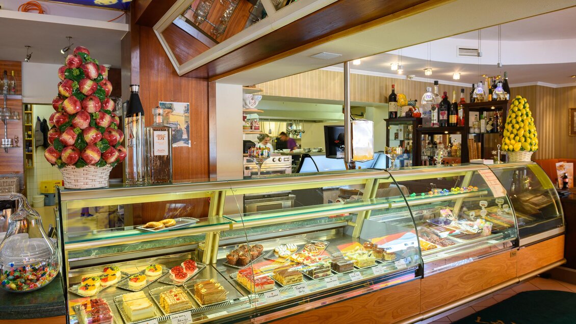 Ein gemütliches Café mit einer Theke voller köstlicher Torten und Süßigkeiten. Im Hintergrund sind Getränke und eine schöne Dekoration zu sehen. | © Restaurant-Cafe Landgraf