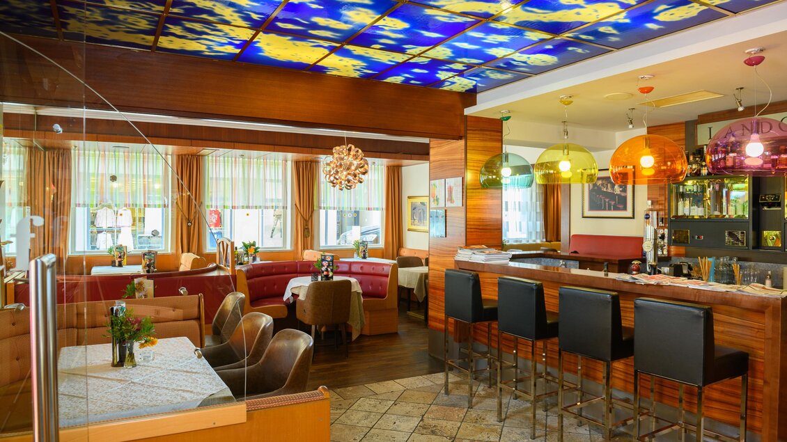 Ein modernes Restaurant mit einer einladenden Bar und bunten Lampen. Die Kombination aus Holz und farbenfrohen Elementen sorgt für eine gemütliche Atmosphäre. | © Restaurant-Cafe Landgraf