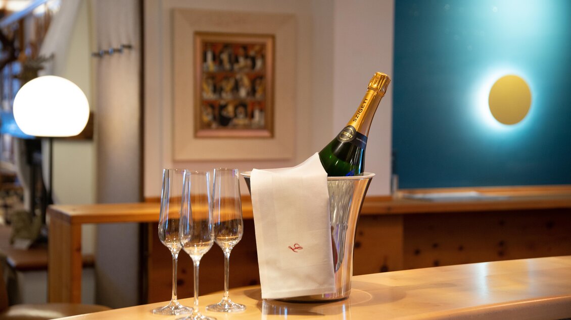 Eine Flasche Champagner steht in einem Eisbehälter neben drei Gläsern. Der Hintergrund zeigt eine elegante Bar mit einem modernen Design. | © Restaurant-Cafe Landgraf