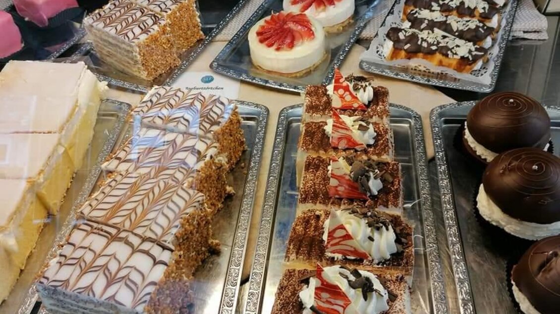 Bunte Süßigkeiten und Kuchen in einer Auslage. Die Auswahl enthält verschiedene Schichten und Aromen, darunter Erdbeeren und Schokolade. | © Restaurant-Cafe Landgraf