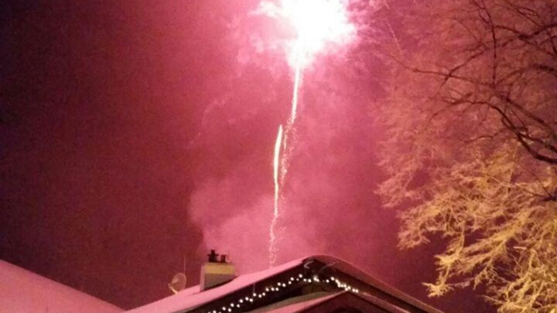 Ein gemütliches Häuschen im Schnee mit Menschen, die feiern. Strahlende Feuerwerke erhellen den Nachthimmel. | © Sautrog-Alm