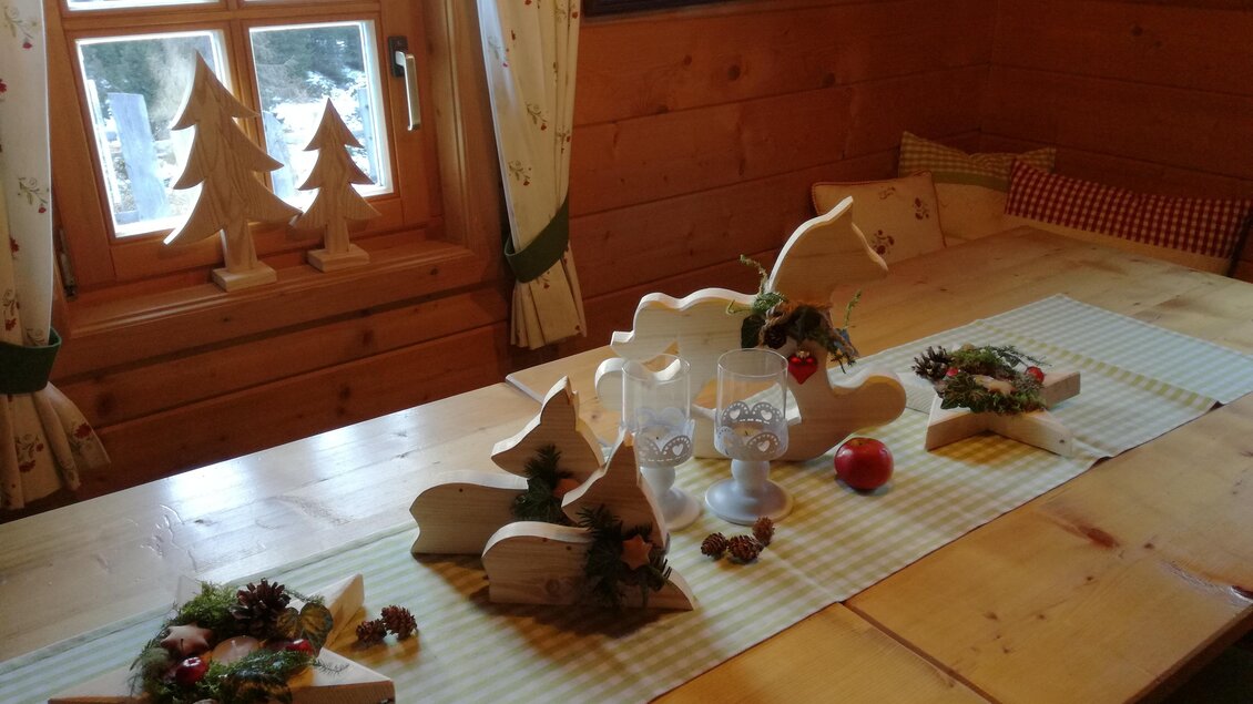 Ein festlich dekorierter Tisch in einer gemütlichen Holzstube. Auf dem Tisch stehen verschiedene Holzsterne und kleine Dekorationen, die eine warme Atmosphäre schaffen. | © Familie Brugger