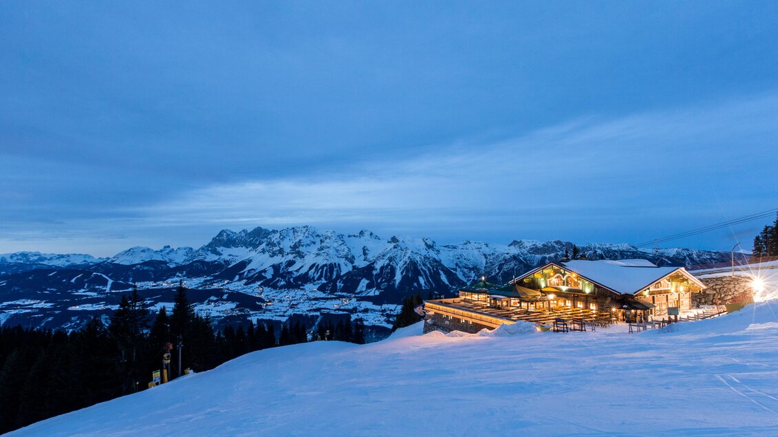 Eine alpine Hütte in der schneebedeckten Landschaft bei Dämmerung. Im Hintergrund sind majestätische Berge zu sehen. | © Dominik Steiner