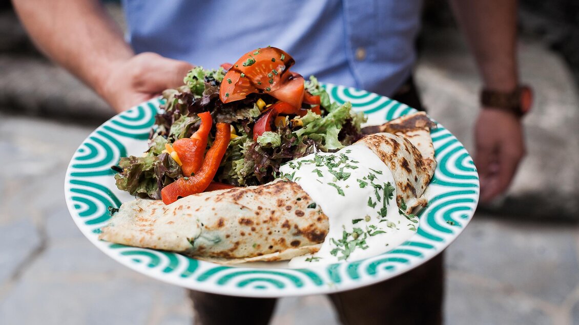 Ein Teller mit frisch zubereiteten Pfannkuchen, serviert mit einem bunten Salat. Der Salat enthält Gemüse wie Paprika und Tomaten und wird mit einer Sahnesoße ergänzt. | © Studio Brighten Alexander Rauch
