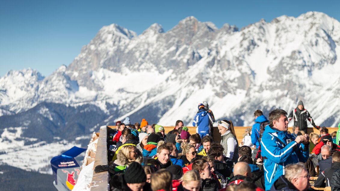 Ein belebter Aussichtspunkt in den Bergen mit zahlreichen Menschen. Im Hintergrund sind schneebedeckte Berge und ein strahlend blauer Himmel zu sehen. | © Harald Steiner