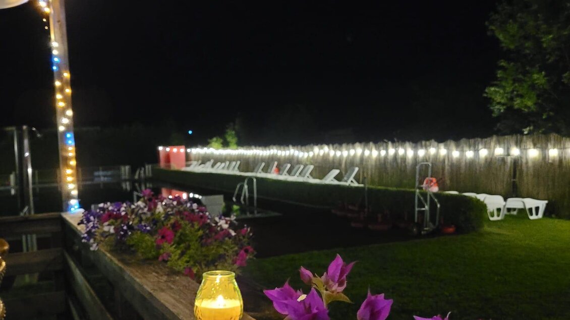 Ein gemütlicher Außenbereich bei Nacht, beleuchtet von Lichterketten. Bunte Blumen und eine sanfte Beleuchtung schaffen eine einladende Atmosphäre. | © Tim Fuchsberger