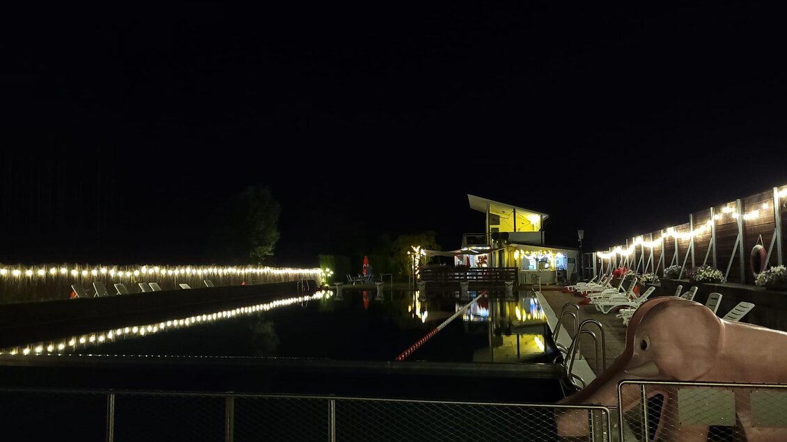 Ein ruhiger Poolbereich bei Nacht mit sanfter Beleuchtung. Im Hintergrund ist ein Gebäude mit weißen Lichtern zu sehen. | © Tim Fuchsberger