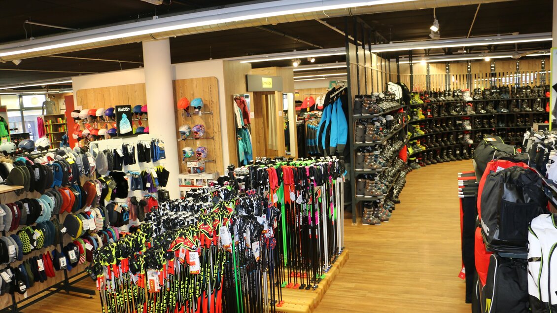 Ein gut sortierter Sportartikelhandel mit einer Vielzahl von Ausrüstungen. Auf beiden Seiten sind Regale mit Kleidung, Rucksäcken und Sportgeräten zu sehen. | © Sport 2000 Rankl Schladming