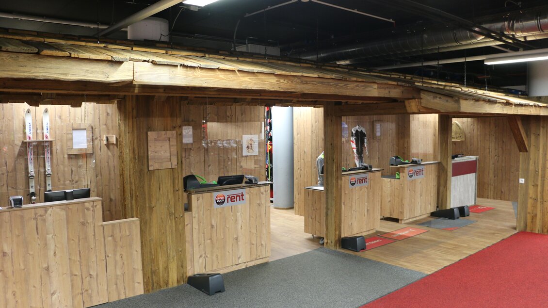 Ein Skiverleih mit Holzelementen und mehreren Empfangstresen. Der Boden ist mit Teppich in Rot und Grau ausgelegt. | © Sport 2000 Rankl Schladming