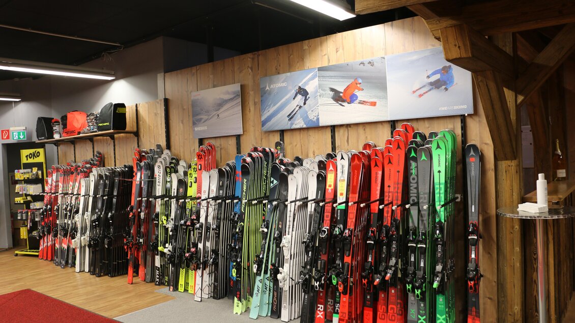 Ein Skiverleih mit einer großen Auswahl an Skiern in verschiedenen Farben. An der Wand hängen Bilder von Skifahrern in Aktion. | © Sport 2000 Rankl Schladming