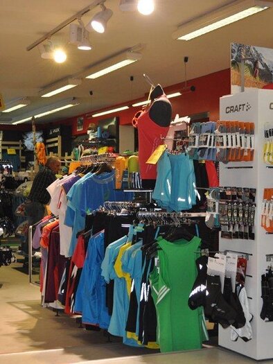 Ein Sportgeschäft mit einer bunten Auswahl an Sportbekleidung und Zubehör. Die Regale sind ordentlich angeordnet und gut beleuchtet. | © Sport Scherz