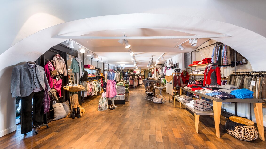 Ein modisches Geschäft mit einer Vielzahl von Bekleidung und Accessoires. Der Holzfußboden und die Beleuchtung schaffen eine einladende Atmosphäre. | © Steirerland Tracht & Leder