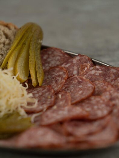 A plate with sausage, fresh bread, and pickled vegetables. There are also some tomatoes and sauerkraut. | © Perner Alexandra