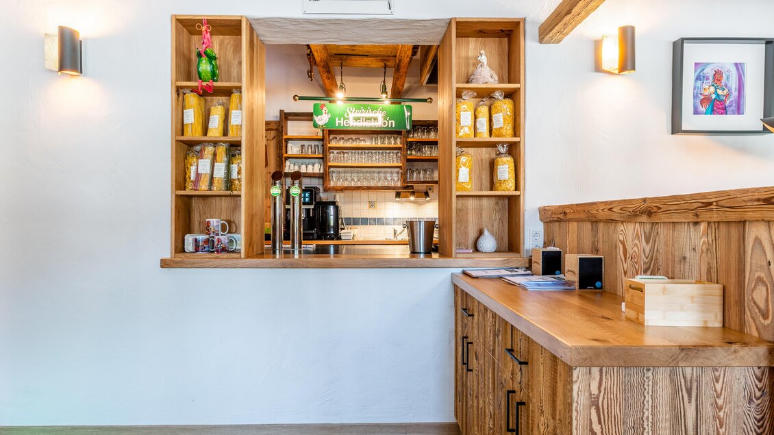 Ein einladender Raum mit Holzregalen, die mit verschiedenen Getränken gefüllt sind. Die gemütliche Bar ist hell und freundlich gestaltet, ideal für eine entspannte Atmosphäre. | © Steirische Hendlstub'n