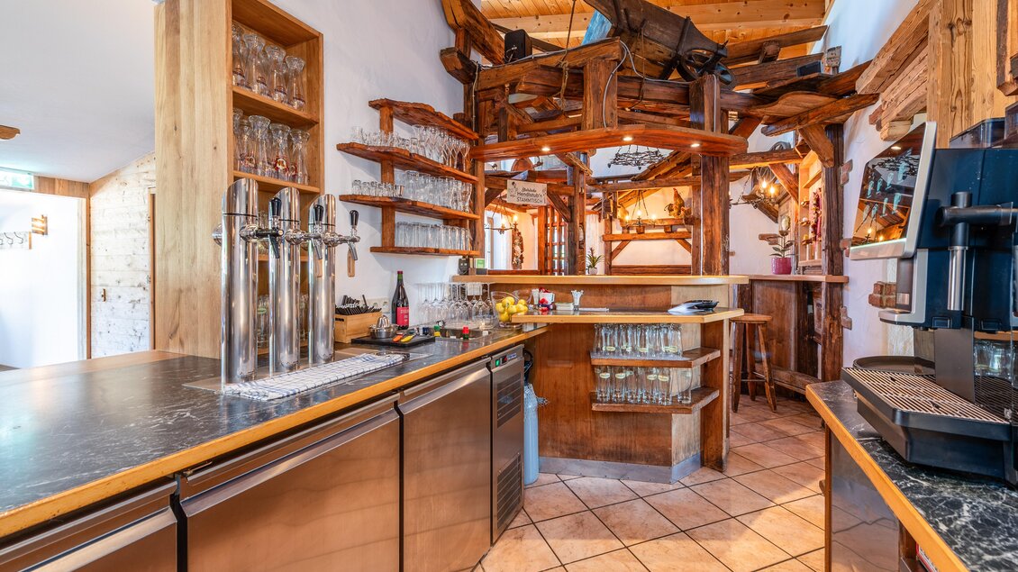 Eine gemütliche Bar mit Holzregalen und einer künstlerischen Einrichtung. Thekenbereiche und eine moderne Kaffeemaschine runden das Bild ab. | © Steirische Hendlstub'n