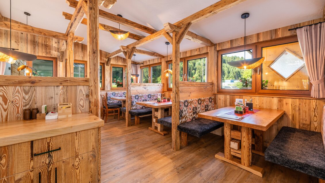 Ein gemütliches Restaurant mit rustikalem Holzinterieur und großen Fenstern. Es gibt Tische und Bänke, die eine einladende Atmosphäre schaffen. | © Steirische Hendlstub'n