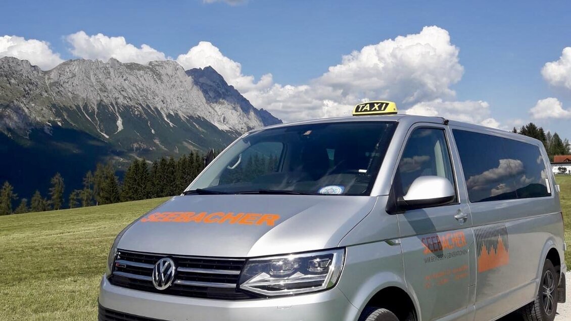 Ein silberner VW-Taxi-Van steht auf einem Schotterweg in einer malerischen Berglandschaft. Die Wolken am blauen Himmel verleihen der Szene einen entspannenden Eindruck. | © Claudia Seebacher
