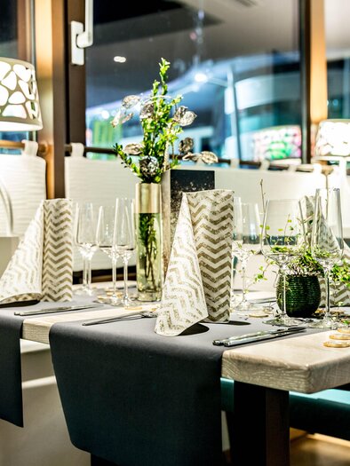 An elegantly set table in a modern restaurant. The table decoration includes glassware and plants to create a cozy atmosphere. | © TUI BLUE