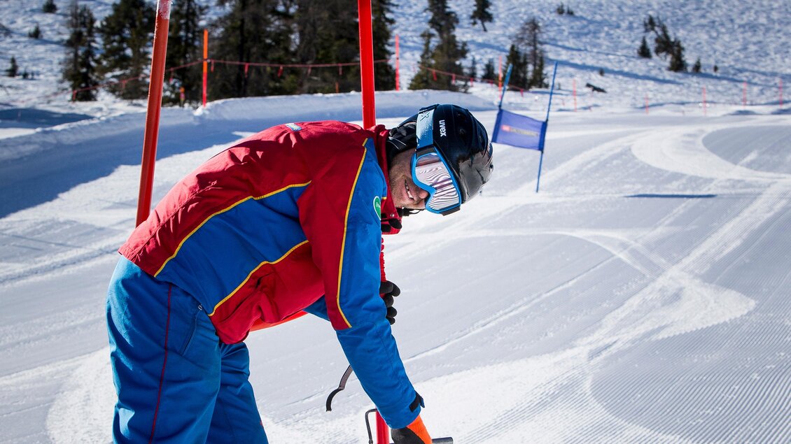 Ein Sportler steht auf Skiern und bereitet sich auf einen Slalomlauf vor. Die Umgebung ist schneebedeckt mit klarem blauen Himmel. | © Tom Lamm