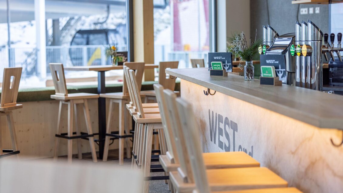 Eine moderne Bar mit Holzmöbeln und einer stilvollen Theke. An der Wand sind Zapfhähne und digitale Bestellsysteme zu sehen. | © Harald Steiner