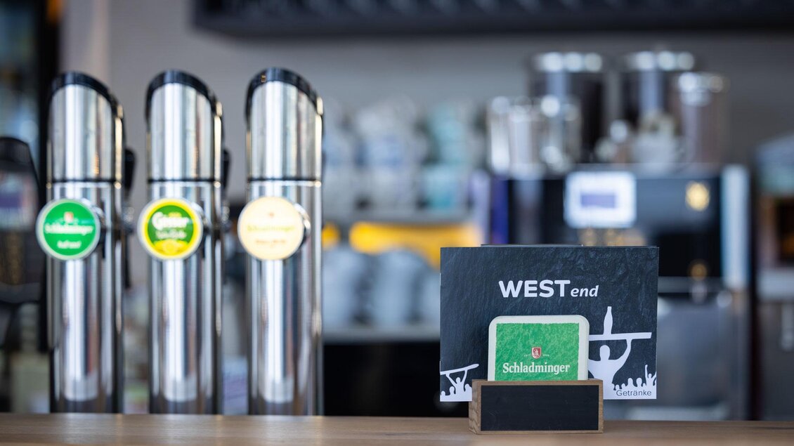 Ein Thekenbereich mit mehreren Getränkespendern und einer Tafel mit der Aufschrift "WESTend". Im Hintergrund sind weitere Ausstattungen einer Bar sichtbar. | © Harald Steiner