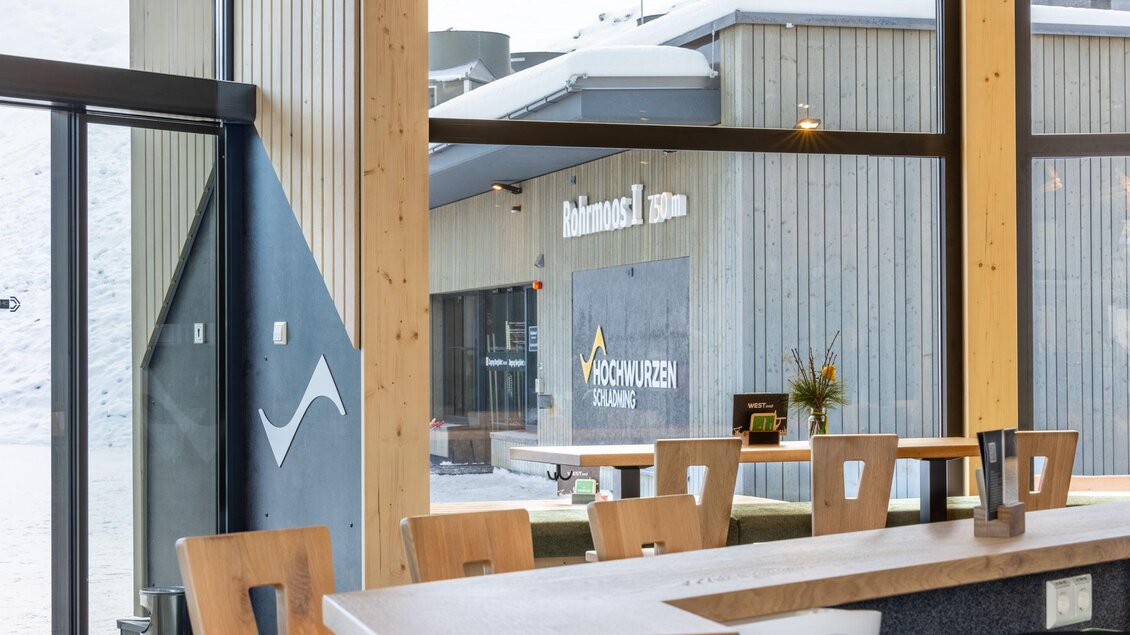 Ein modernes Café mit Holzinterieur und Blick auf die Berglandschaft. Große Fenster bieten viel Tageslicht und eine einladende Atmosphäre. | © WESTend Lounge