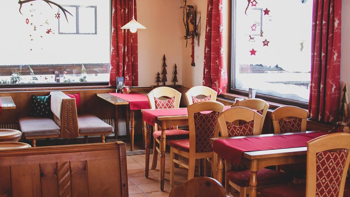 Gemütliches Gasthaus mit Holzdecke, roten Vorhängen und festlich gedeckten Tischen – warme, einladende Atmosphäre. | © Foto Tom