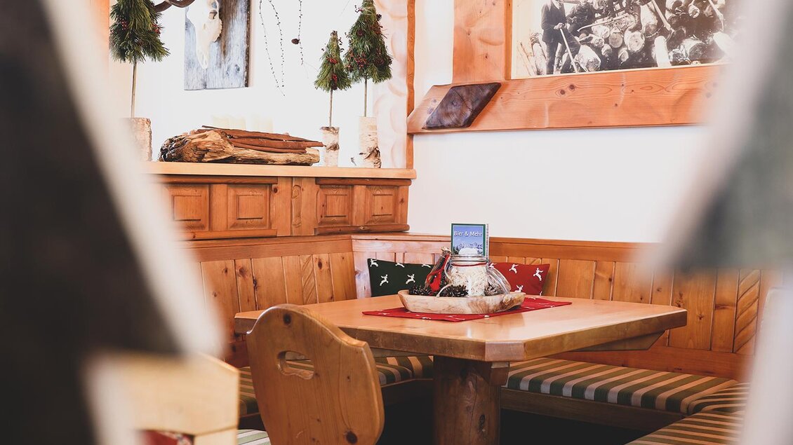 Eine bepolsterte Sitzgarnitur mit Tisch aus Holz. Im Vordergrund stechen zwei Filz-Tannebäume hervor. | © Foto Tom