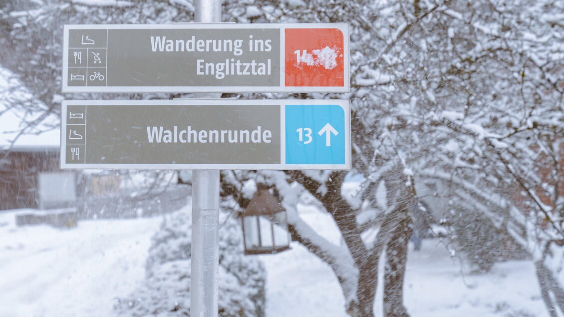 Ein Wegweiser im verschneiten Winterland zeigt zwei Wanderwege. Der obere Weg führt ins Englitztal, der untere zur Walchenrunde. | © Christoph Lukas