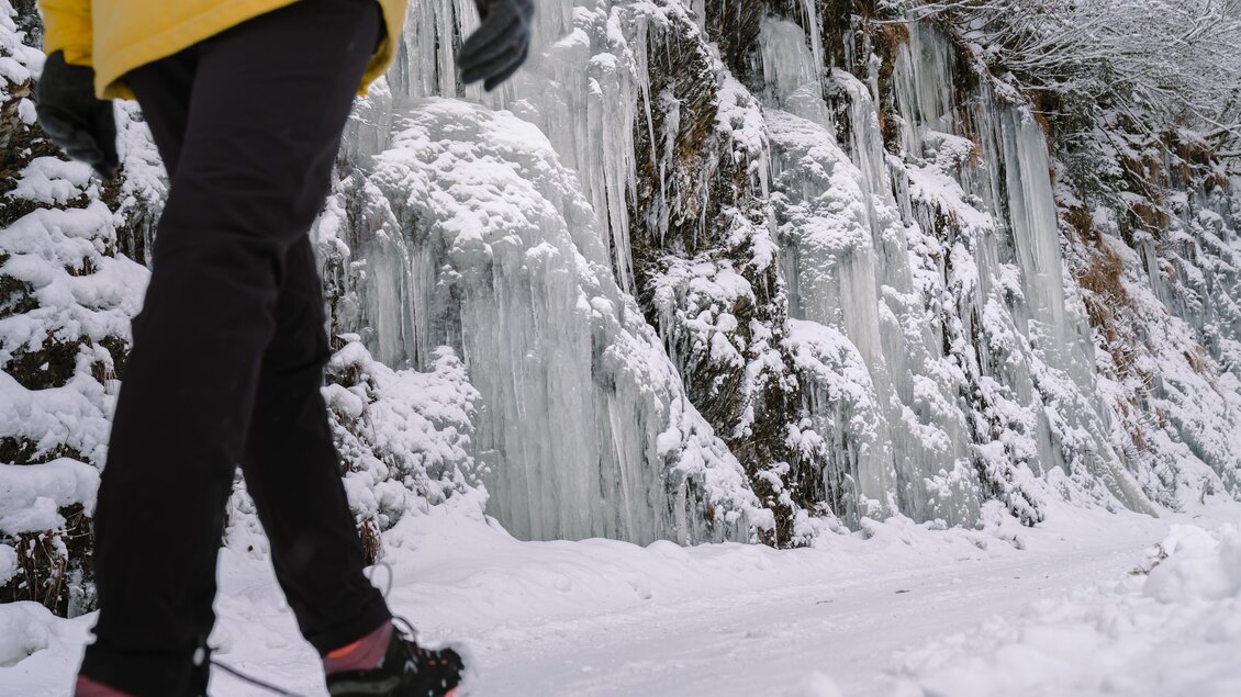 Eine Person geht auf einem verschneiten Weg entlang gefrorener Eisplatten. Die Umgebung ist winterlich mit Schnee und Eis. | © Christoph Lukas