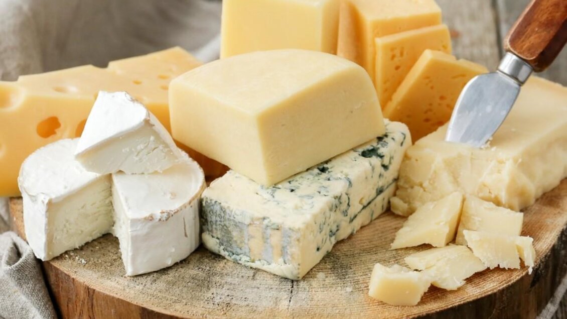 Eine Auswahl verschiedener Käsesorten auf einem Holzbrett. Dazu liegt ein Käsemesser. | © Walcheralm