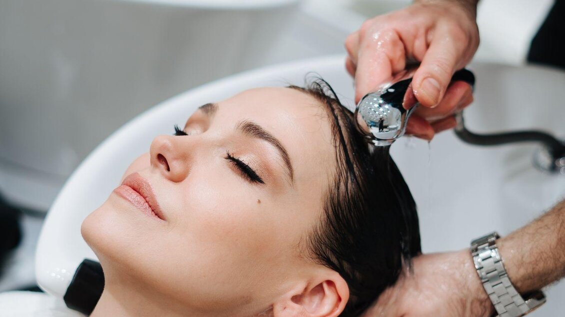 Eine Frau erhält eine Haarwäsche in einem Salon. Sie entspannt sich, während ein Friseur sanft ihre Haare reinigt. | © Wohlfühlfriseur Rohrmoser