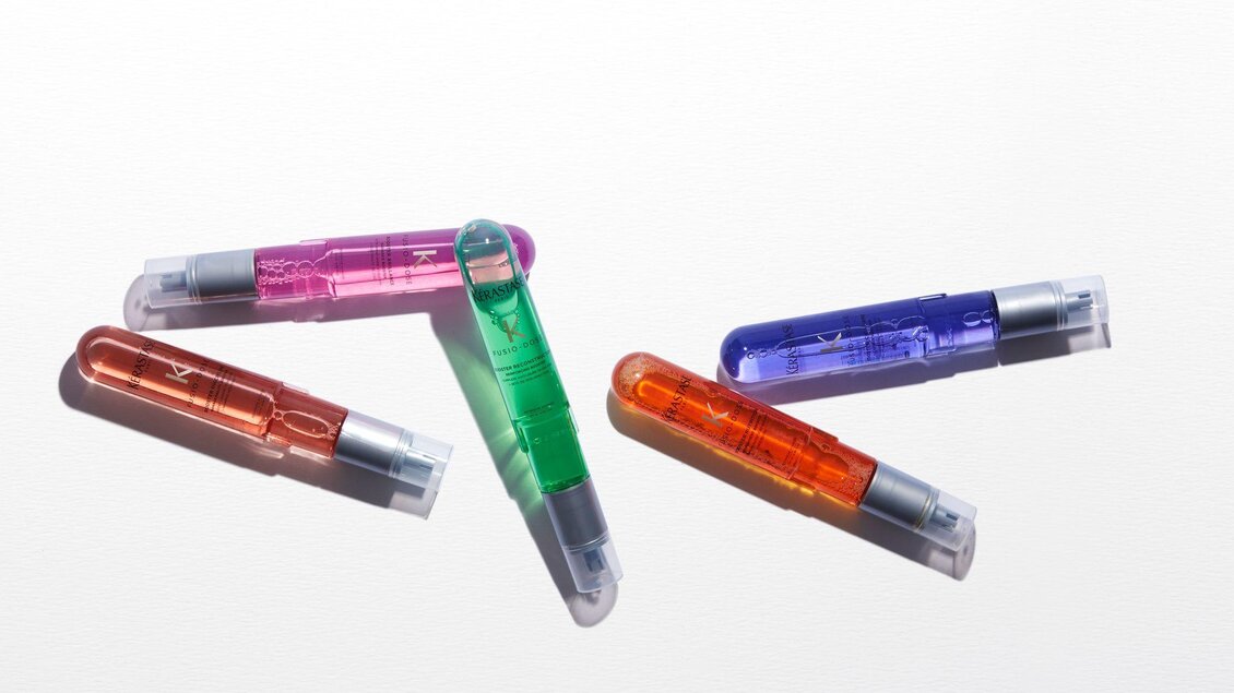 Fünf bunte Stifte liegen auf einem weißen Hintergrund. Die Farben umfassen Pink, Grün, Orange, Blau und Lila. | © Wohlfühlfriseur Rohrmoser