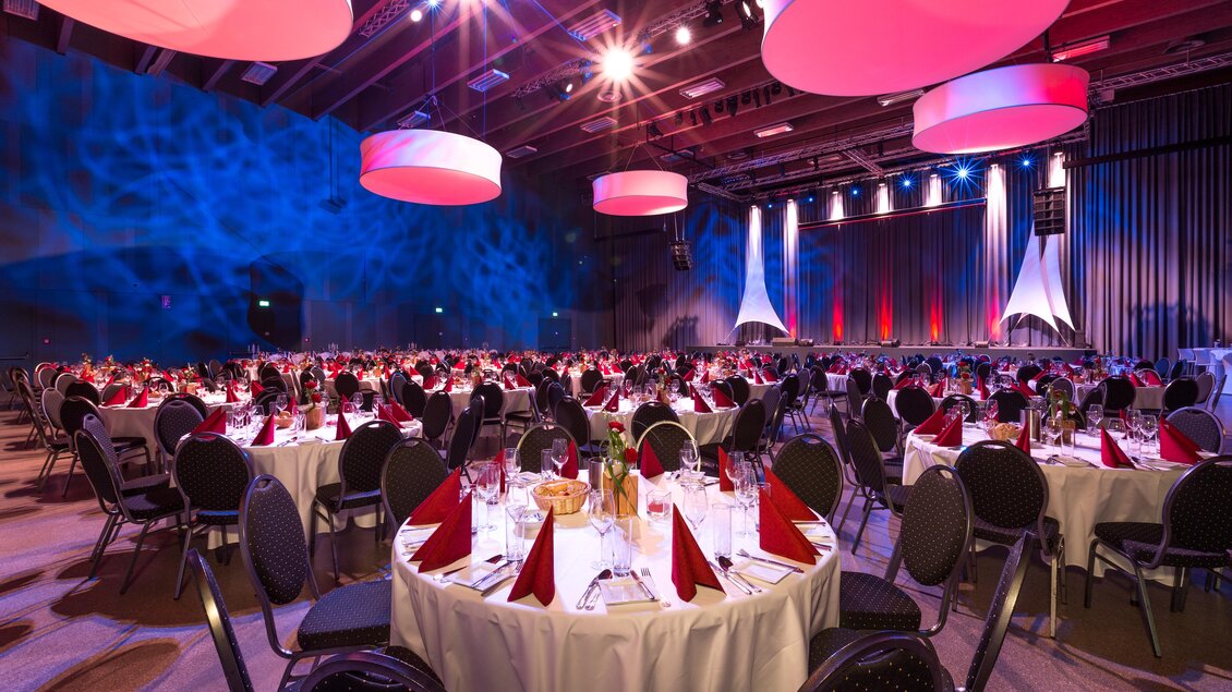 Eleganter Veranstaltungssaal mit festlich gedeckten Tischen. Rote und violette Beleuchtung schafft eine besondere Atmosphäre. | © Harald Steiner