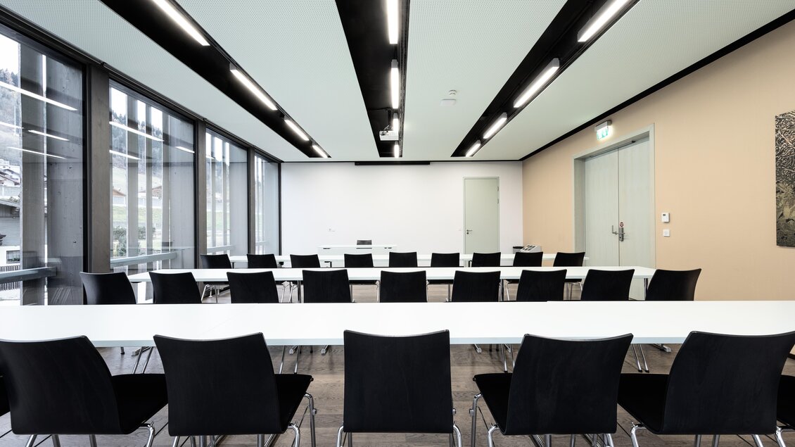 Ein moderner Konferenzraum mit langen Tischen und schwarzen Stühlen. Große Fenster sorgen für viel Tageslicht. | © Harald Steiner 