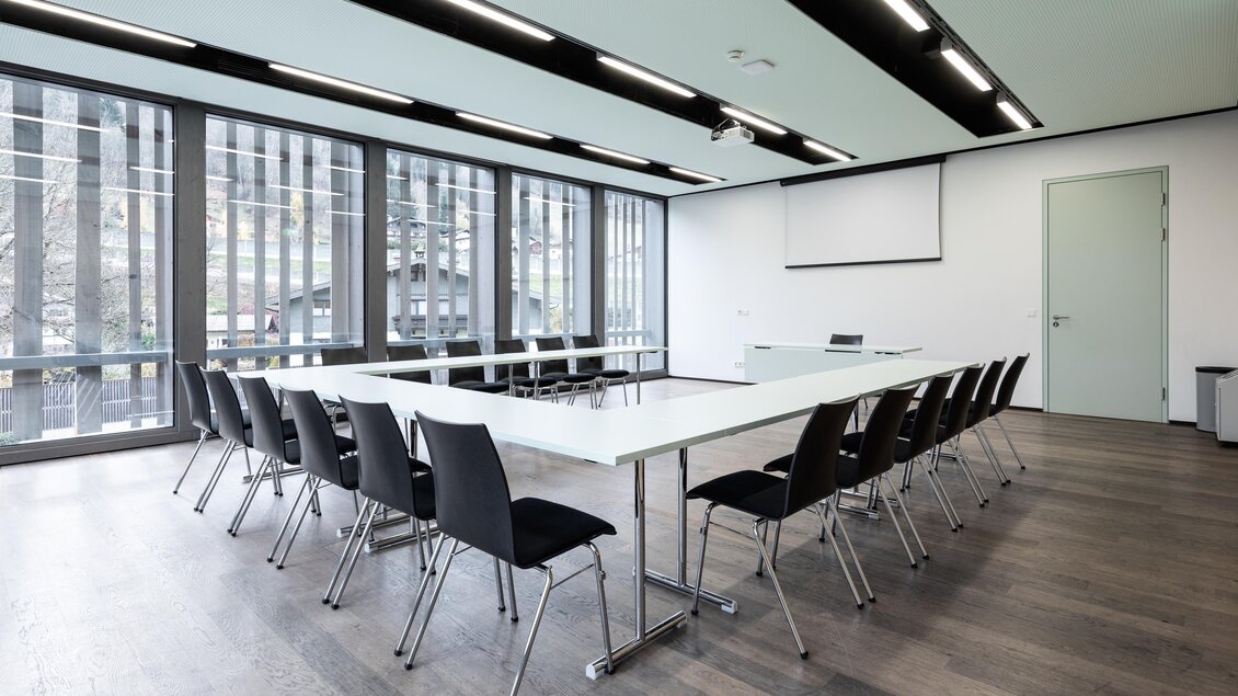 Ein moderner Konferenzraum mit einem langen Tisch und schwarzen Stühlen. Große Fenster sorgen für viel Tageslicht. | © Harald Steiner 