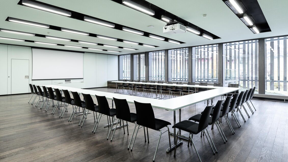 Ein moderner Besprechungsraum mit einem langen Tisch und vielen Stühlen. Große Fenster sorgen für viel Tageslicht. | © Harald Steiner 
