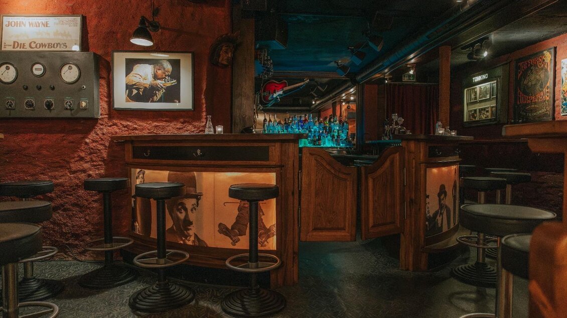 Eine gemütliche Bar mit Holztheke und dunkelroten Wänden. Die Beleuchtung ist gedämpft und schafft eine entspannte Atmosphäre. | © Daniela Pattermann